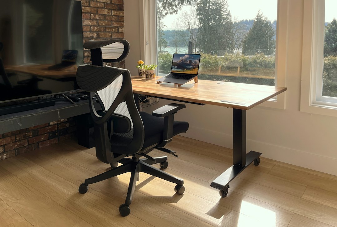 a desk with a laptop on it in front of a window